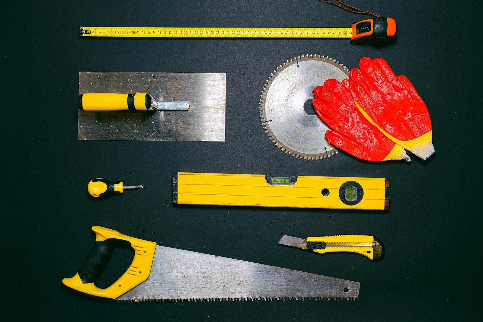 A set of construction hand tools arranged in a flat lay on a dark background. Ideal for DIY projects.